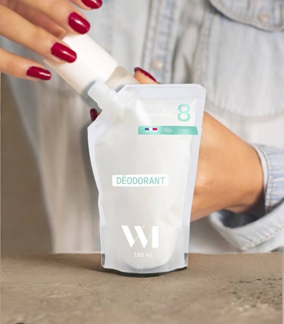 Femme aux ongles rouges remplissant un flacon réutilisable de Déodorant WI 180 ml, recharge éco.
